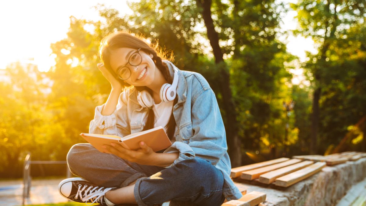 High school student sitting on dock reading book