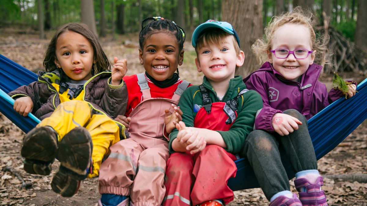 Four young students from South Mountain Nature School sit on a log.